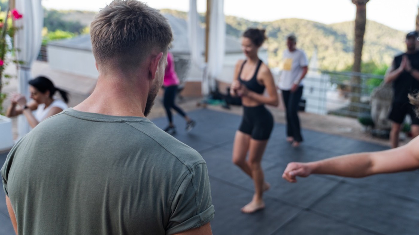 Jonny watching a group work through a movement session on a terrace