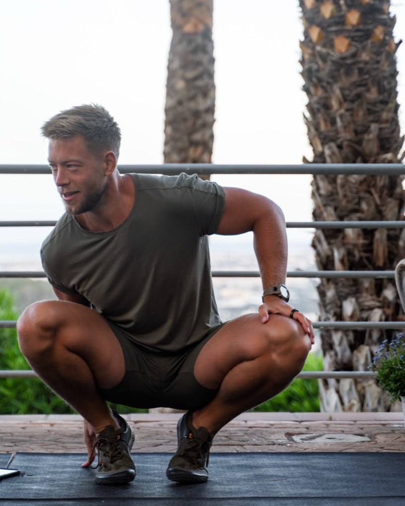Jonny Brakels holding a deep squat on an outdoor terrace